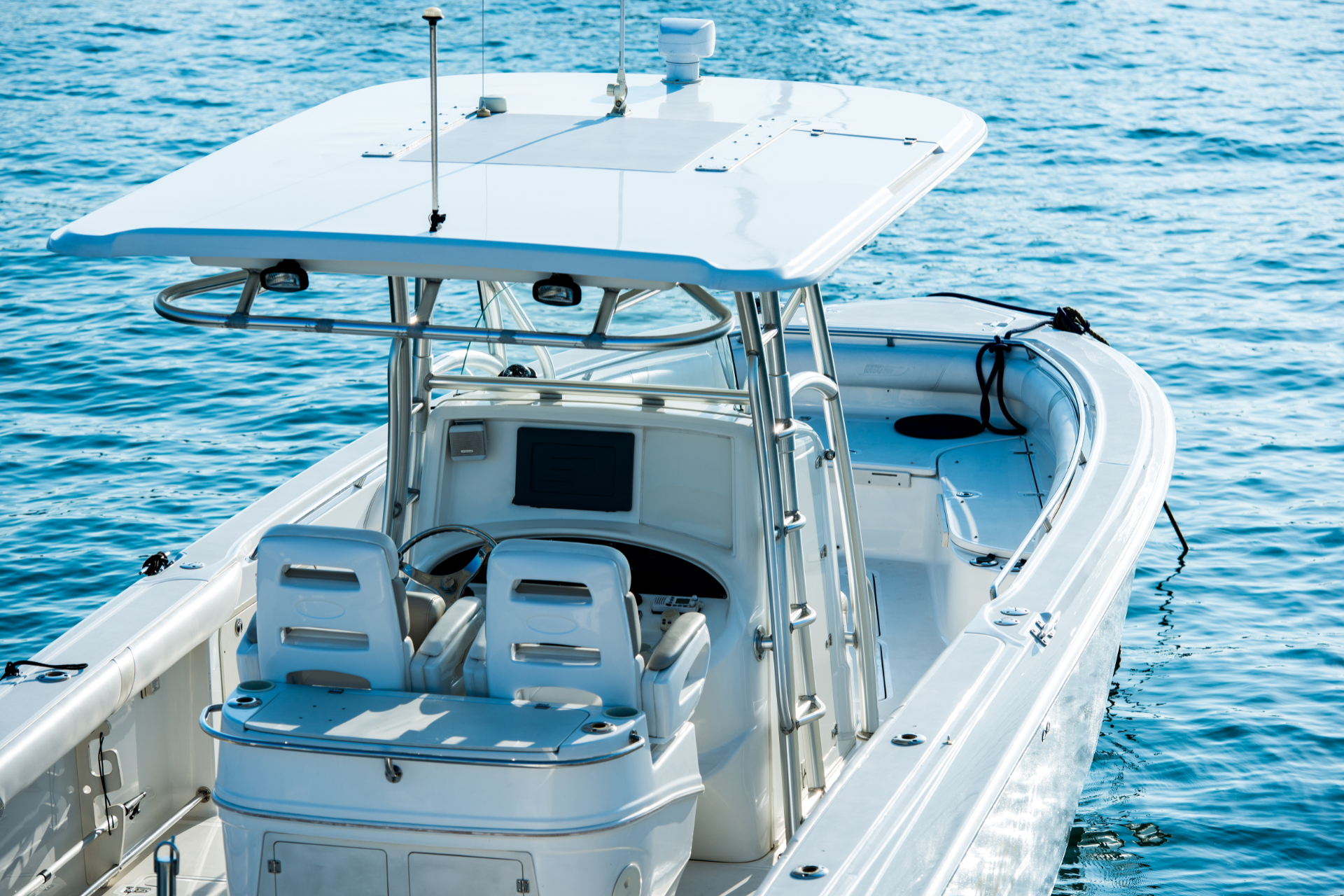 A white center console motorboat with a T-top roof and two captain's chairs sits on calm blue water.