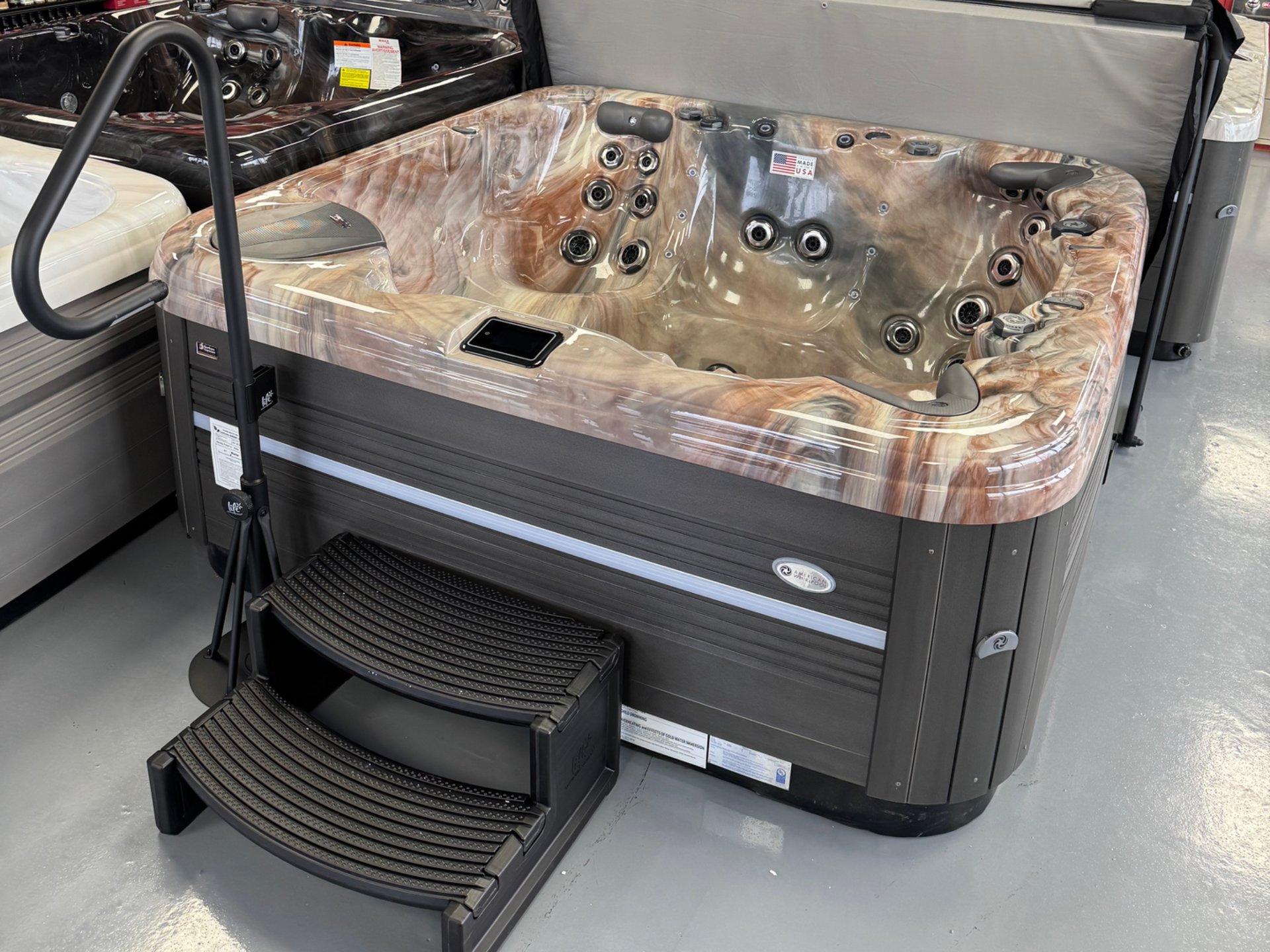 Hot tub with brown and tan interior, dark grey exterior, and steps.