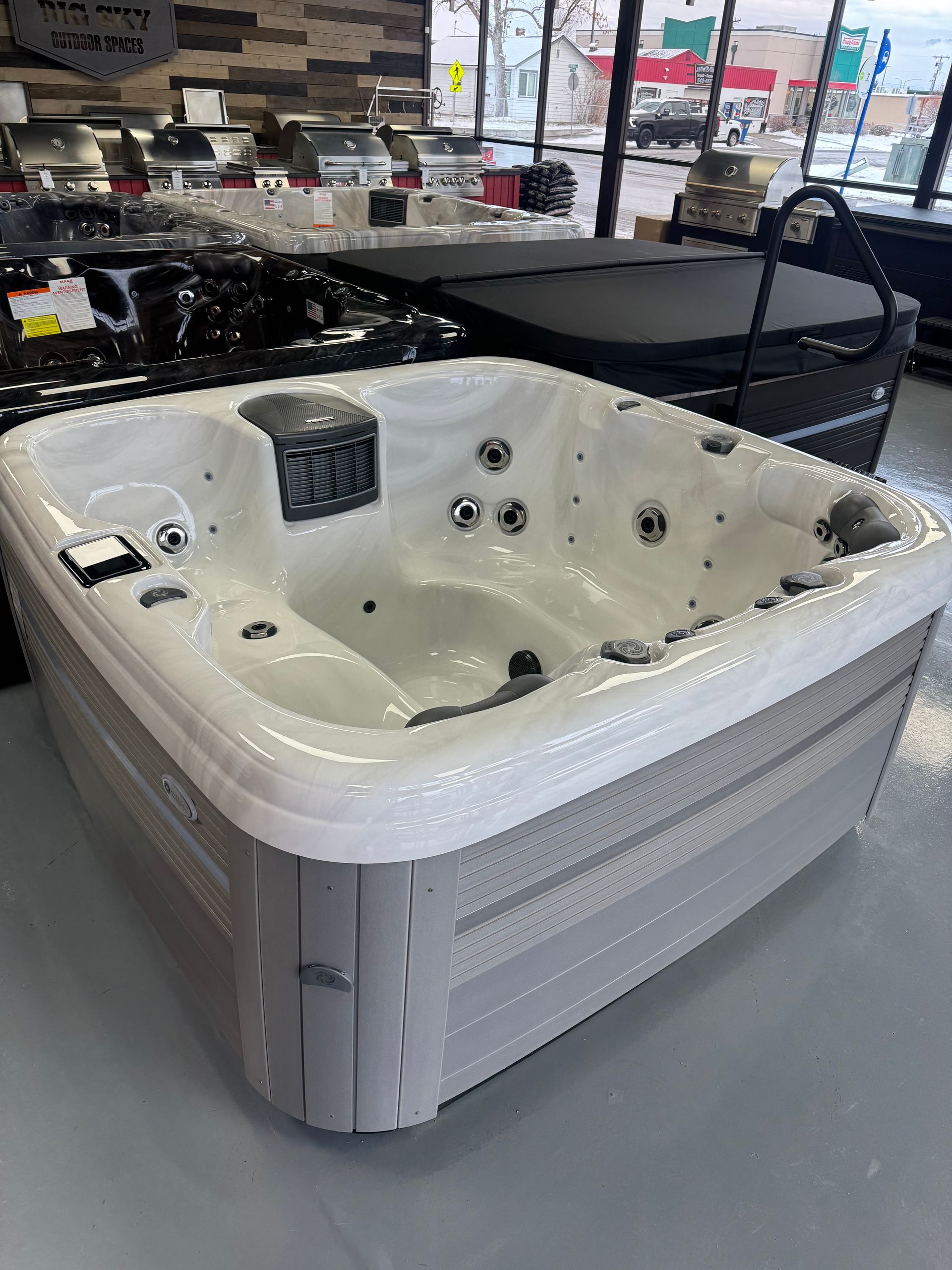 White and gray hot tub on display in a showroom, featuring jets and control panel.