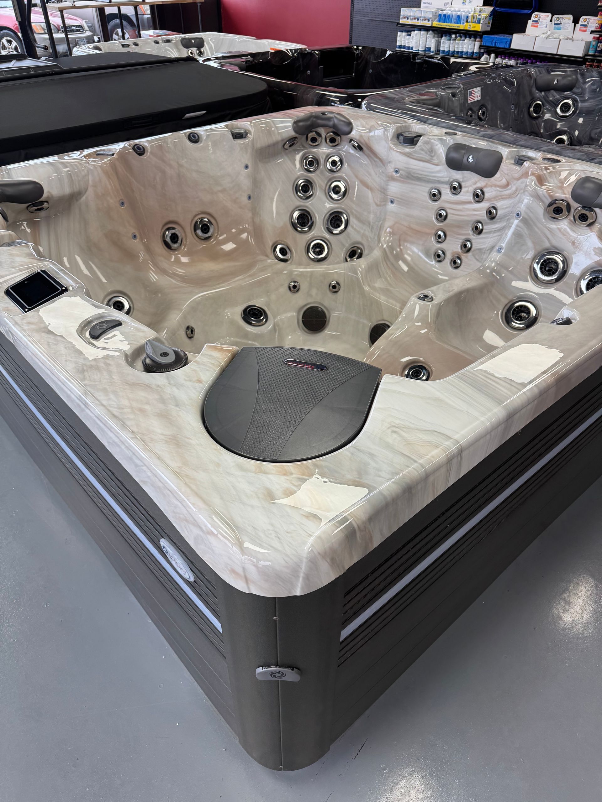 Tan and grey hot tub with multiple jets in a showroom setting.
