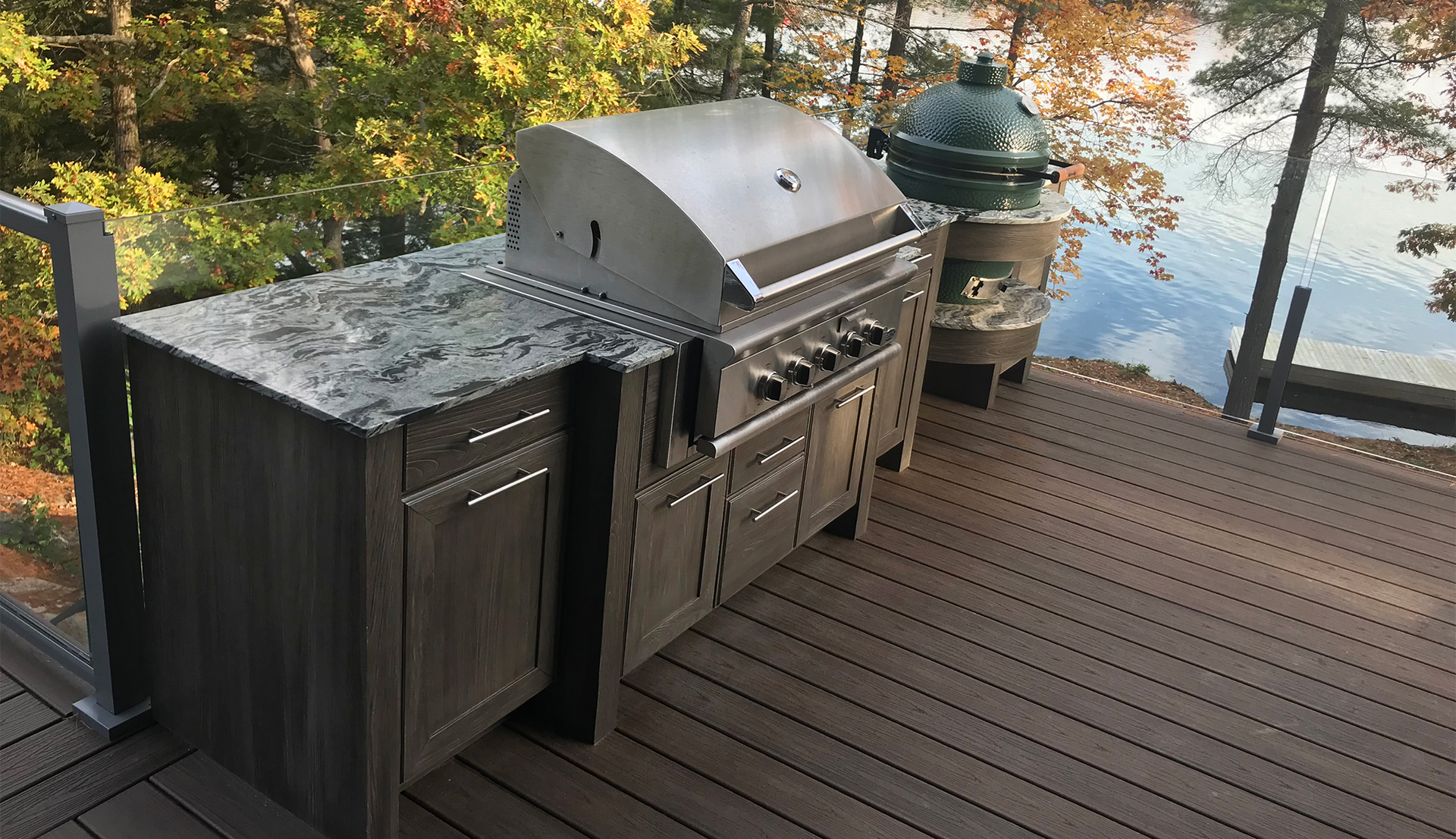 Outdoor kitchen on a deck with grill and Big Green Egg overlooking a lake.