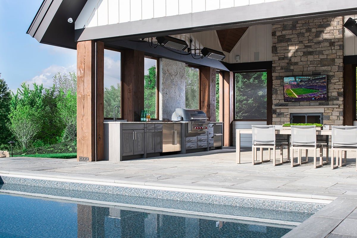 Outdoor kitchen and dining area by a pool. Features grill, fireplace, seating, and a TV.