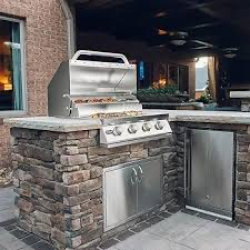 Outdoor kitchen with stainless steel grill, stone facade, and stainless steel doors.