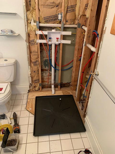 A bathroom with a toilet and a tray on the floor.