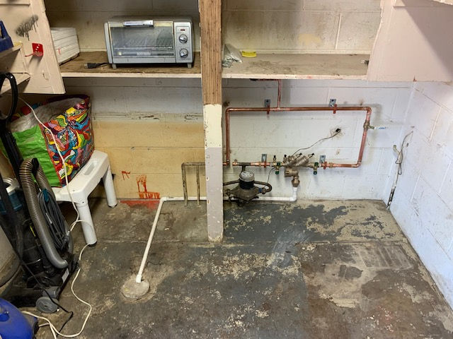 A dirty room with a toaster oven and a vacuum cleaner.