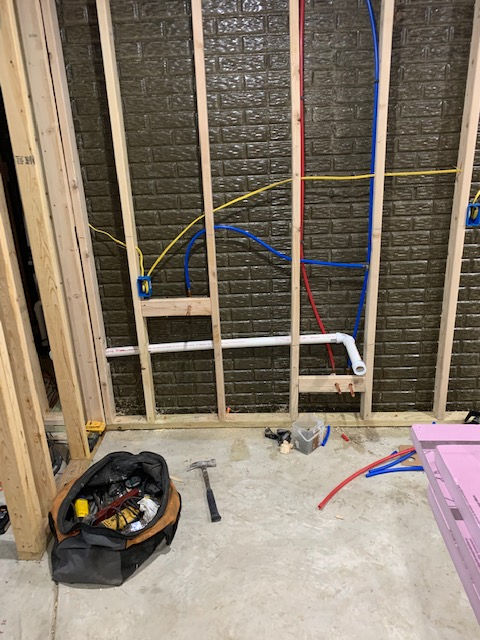 A bag of tools is sitting on the floor in a room under construction.