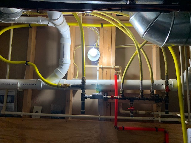 A bunch of pipes and wires are hanging from the ceiling