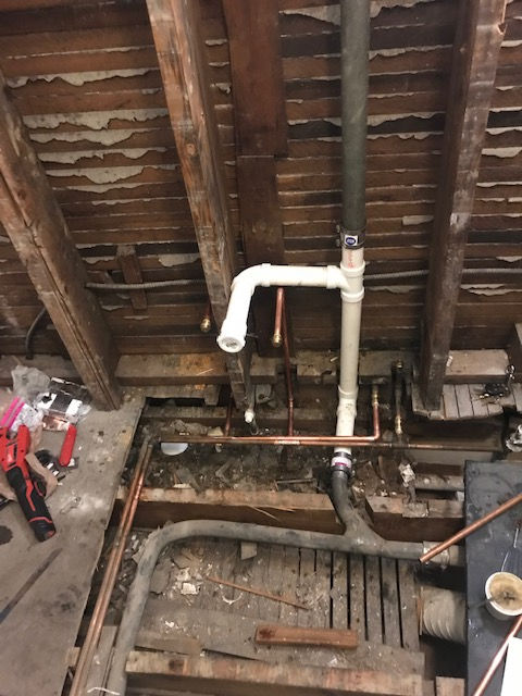 A man is working on a pipe in a wooden room.