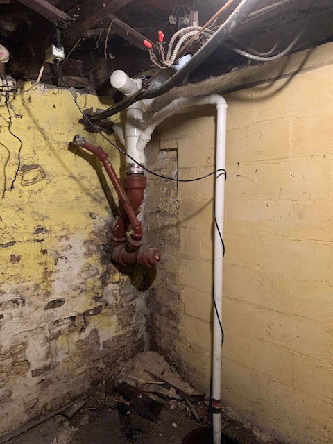 A pipe is hanging from the ceiling in a basement