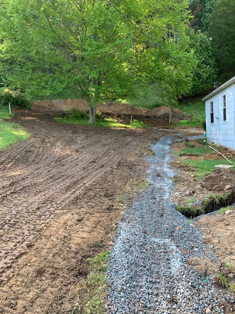 A dirt road leading to a house in the woods.