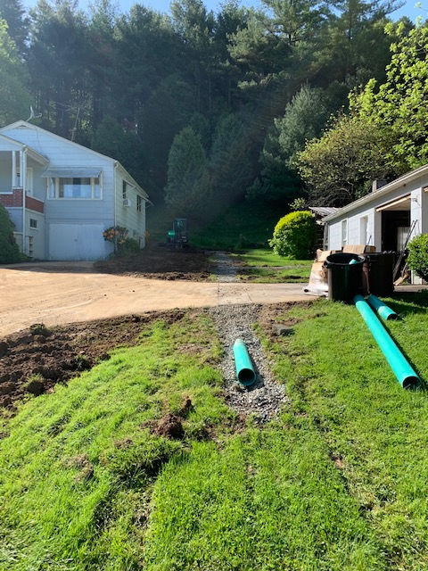 A green pipe is sitting in the grass in front of a house.