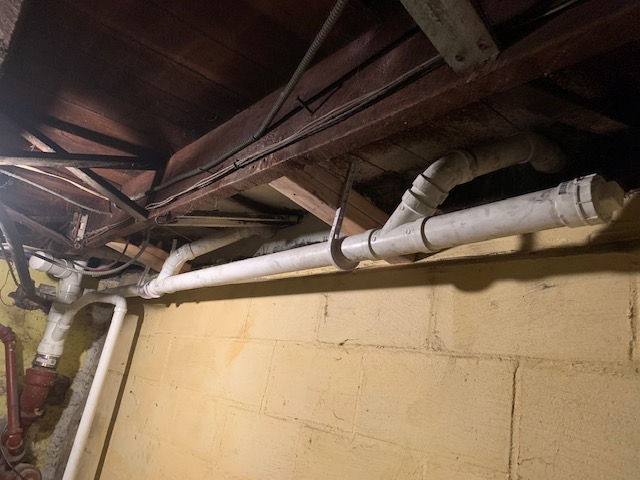 A bunch of pipes are hanging from the ceiling of a building.