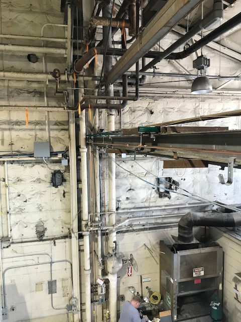 A man is working in a room with lots of pipes