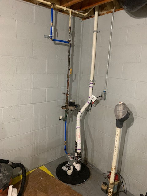 A basement with a lot of pipes and a vacuum cleaner.