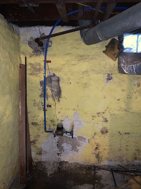 A yellow wall with a blue pipe coming out of it