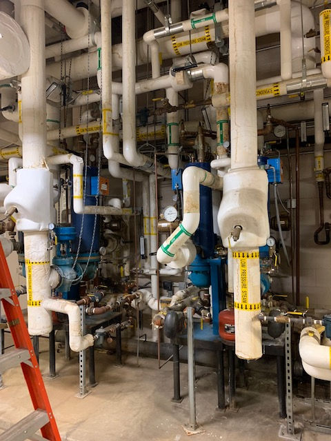 A room filled with lots of pipes and a ladder