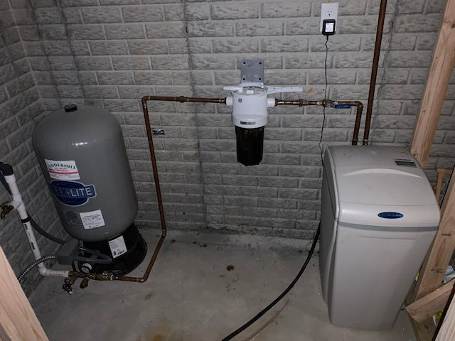 There is a water tank and a water softener in the room.