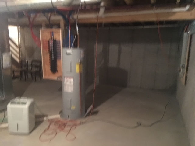 An empty basement with a water heater and a humidifier.