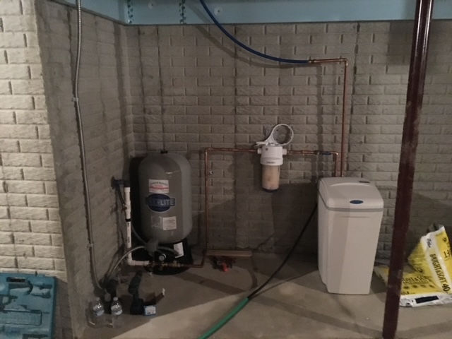 A basement with a water tank and a trash can