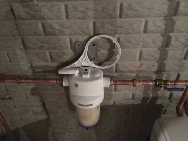 A water filter is attached to a brick wall.