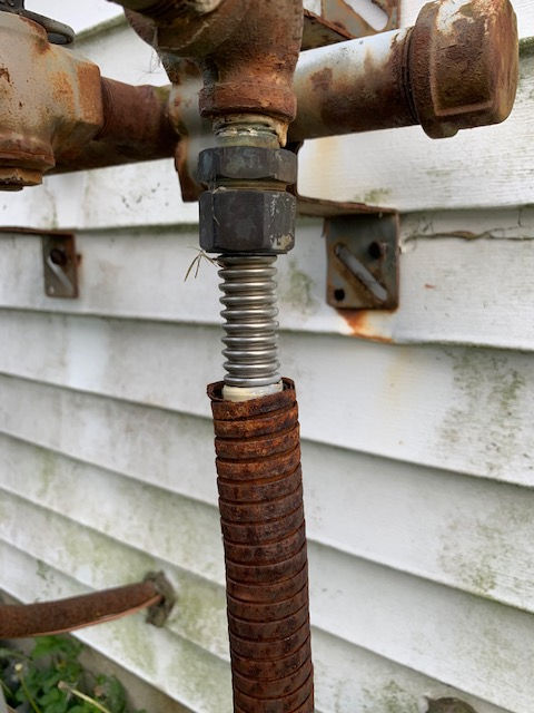A close up of a rusty pipe with a hose attached to it.