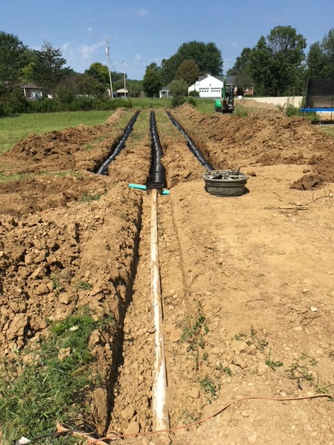 A row of pipes are being installed in a dirt field.