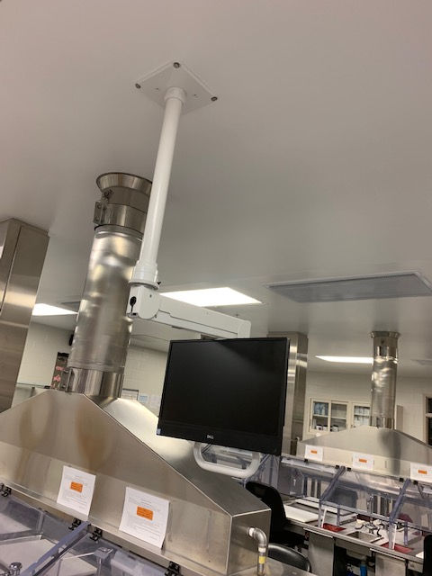A computer monitor is hanging from the ceiling in a clean room