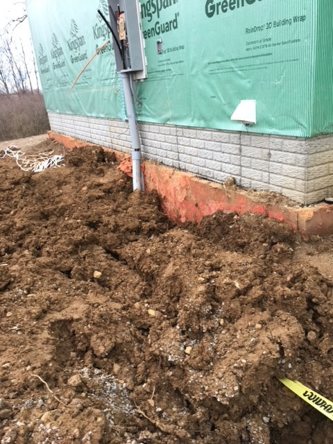 A pile of dirt is sitting in front of a brick building.