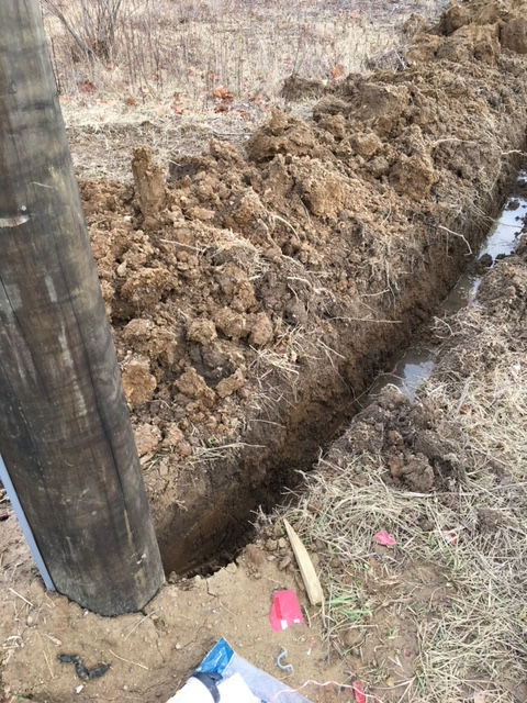 A wooden pole is sitting in the middle of a pile of dirt.