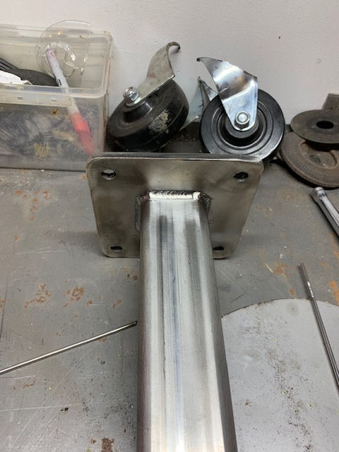 A metal post with wheels attached to it is sitting on a table.