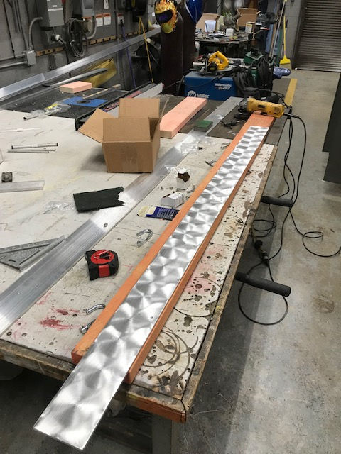 A long piece of metal is sitting on a wooden table