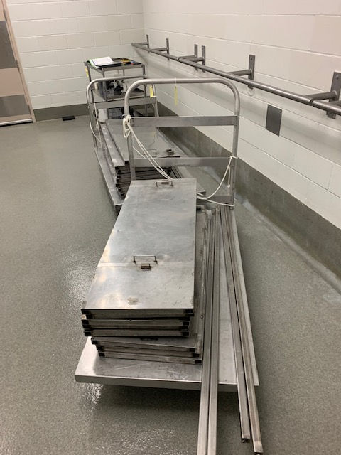 A stack of stainless steel shelves on a cart in a kitchen.