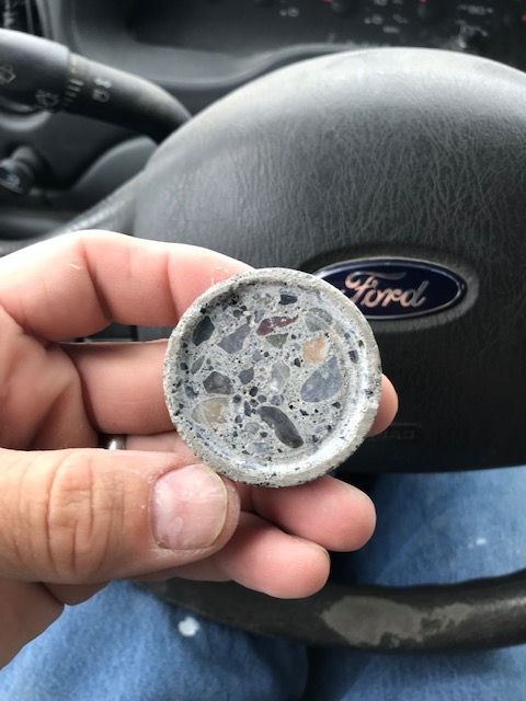 A person is holding a coin in front of a ford logo