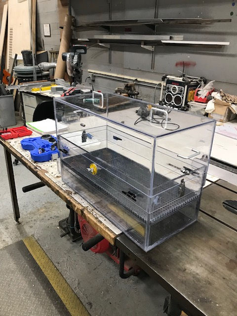 A clear acrylic box is sitting on top of a wooden table.