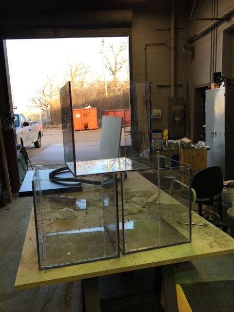 Two glass containers are sitting on a table in a garage