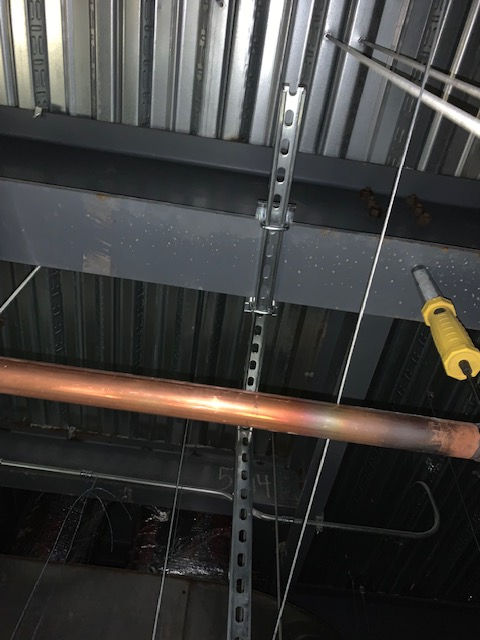 A copper pipe is hanging from the ceiling of a building.