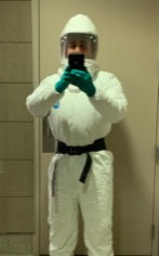 A man in a protective suit is taking a selfie in front of a mirror.