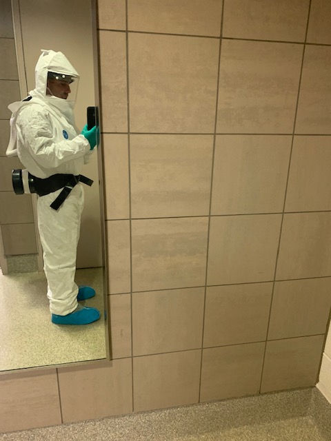 A man in a protective suit is taking a picture of himself in a mirror.