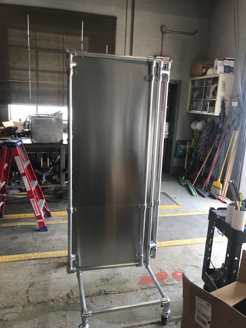 A stainless steel refrigerator is sitting on a cart in a garage.