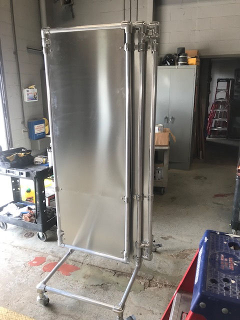 A stainless steel door is sitting on a cart in a garage.