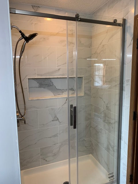 A shower with a sliding glass door and a shower head.