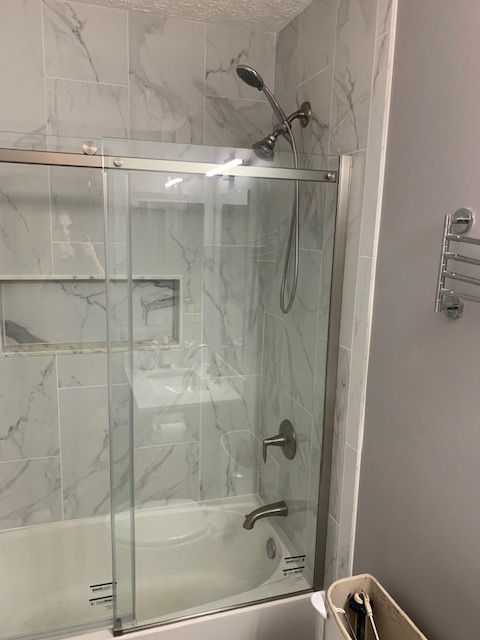 A bathroom with a bathtub and a shower with a sliding glass door.