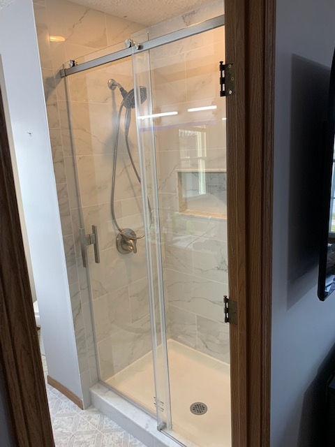 A bathroom with a sliding glass shower door.