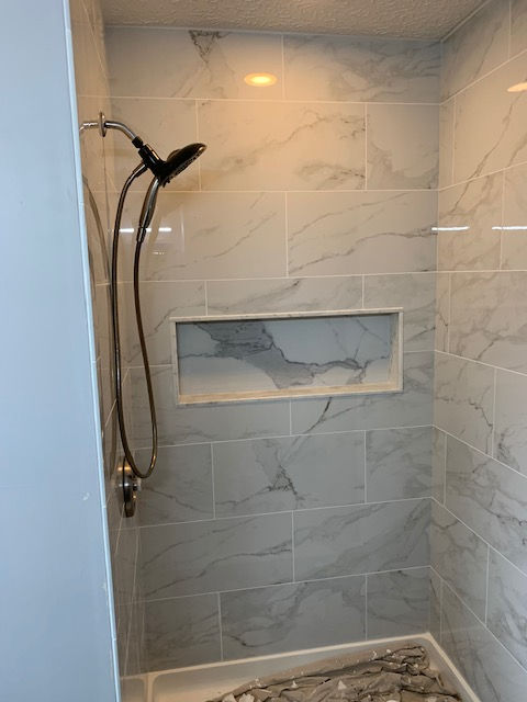 A shower with a shower head and a shelf in the wall.
