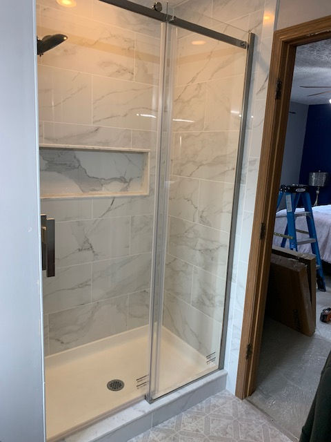 A shower stall with a sliding glass door in a bathroom.