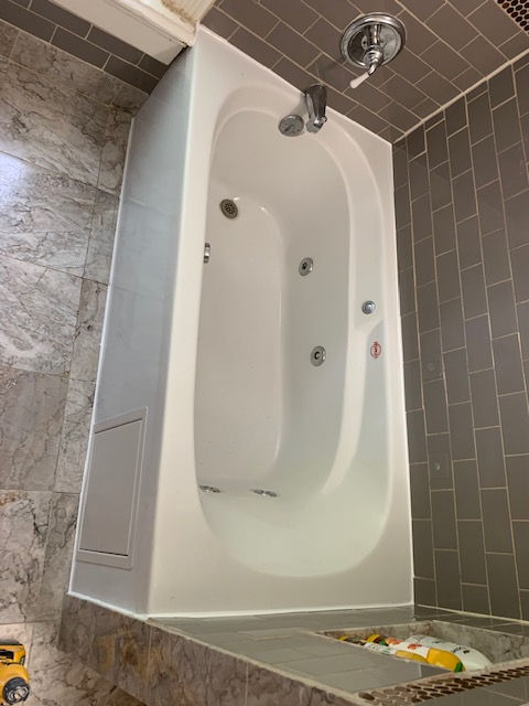 A white bathtub is sitting in a bathroom next to a tiled wall.