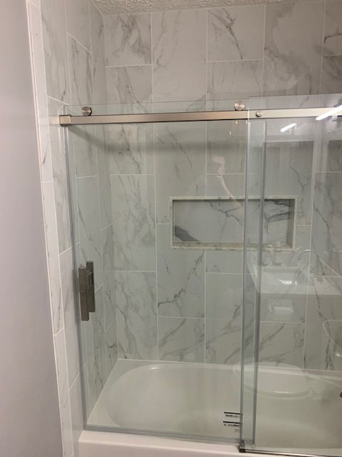 A bathroom with a sliding glass shower door and a bathtub.