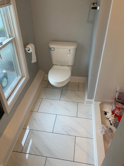 A toilet is sitting in a bathroom next to a window.