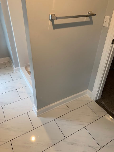 A bathroom with white tiles and a towel rack on the wall.
