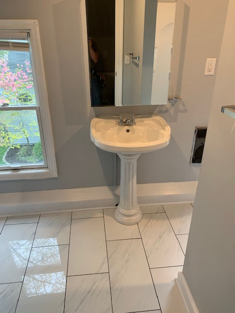 A bathroom with a pedestal sink and a mirror.